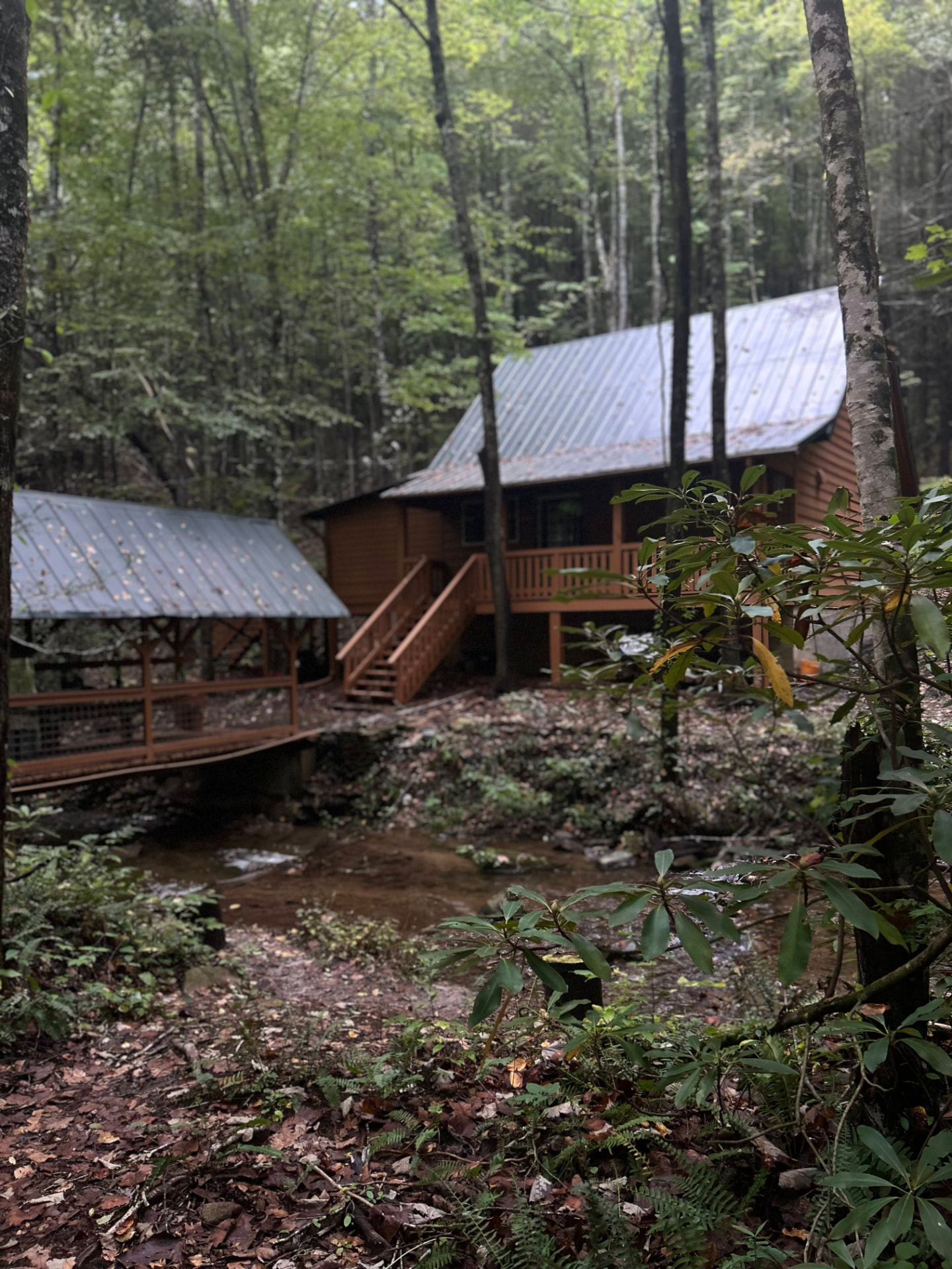 Sherpa Camp log cabin with a metal roof beside a small creek in the North Georgia woods
